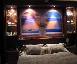 Dormitorio elegante con cama, mural de playa al atardecer, y estantes con adornos iluminados.