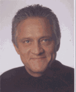 Porträt eines lächelnden Mannes mit grauen Haaren vor hellem Hintergrund.