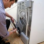 Man repairing the back of a washing machine.