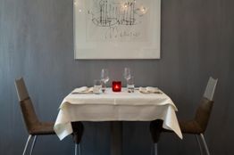 Ein gedeckter Tisch für zwei Personen mit einer roten Kerze in einem eleganten Restaurant.