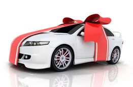 White car wrapped in a large red ribbon bow, resembling a gift.