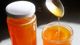 Two jars of honey, one open with a spoon drizzling honey into it.