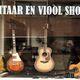 Winkelraam met drie gitaren. Tekst bovenaan: "Gitaar en Viool Shop".