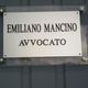 Targa con scritto: "Emiliano Mancino Avvocato" su sfondo metallico.