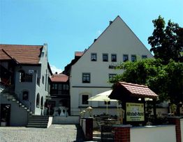 Altstadt-Hotel mit Giebeldach, Treppenaufgang links und Sonnenschirmen im Vordergrund.