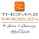 Logo von Thomas Immobilien mit Text: "Spain & Germany Real Estate". Orange und graue Schrift.