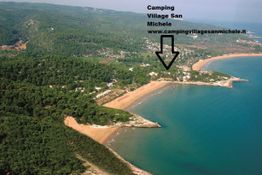 Veduta aerea di una spiaggia e foresta, con freccia verso il Camping Village San Michele.