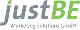 Logo von justBE Marketing Solutions GmbH mit grauem und grünem Text.
