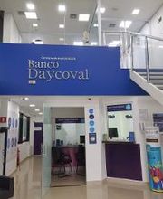 Interior do Banco Daycoval com cartazes na parede e uma escada ao lado.