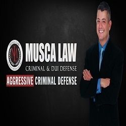 Man in suit with "Musca Law: Aggressive Criminal Defense" text on a black background.