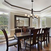 Elegant dining room with dark wood table, eight chairs, chandelier, large mirror, and windows.
