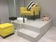 Sala de pedicura con sillón amarillo, flores y velas, sobre plataforma escalonada blanca.