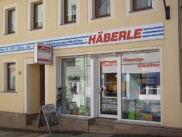 Geschäftsfassade "Häberle" mit Schildern für Telekommunikation und Handy-Center, Fensterfront.