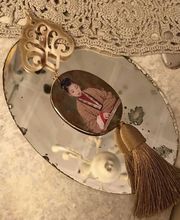 Antiker Handspiegel mit Bild einer Frau in traditioneller Kleidung, goldene Verzierung und Quaste.