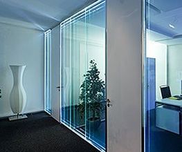 Modernes Büro mit Glastüren, Pflanzen und schlichtem Dekor, lichtdurchflutet und stilvoll.