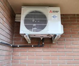 Aire acondicionado Mitsubishi montado en la pared de ladrillo exterior.