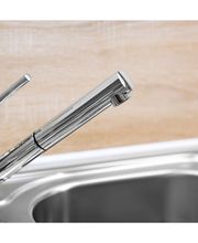 Grifo de cocina moderno de acero inoxidable sobre un fregadero, fondo de pared clara.