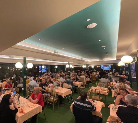 Persone mentre cenano in un grande ristorante affollato con soffitto azzurro.