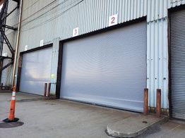 Three large industrial garage doors numbered 1, 2, and 3 on a corrugated metal building.