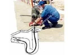 Trabalhador cortando concreto com máquina; esboço de corte em forma de canalização à esquerda.