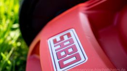 Nahaufnahme eines roten Rasenmähers mit "SABO"-Logo im Gras.