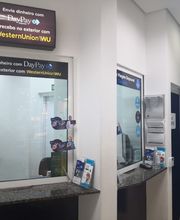 Balcões para envio e recebimento de dinheiro com placas de DayPay e Western Union em um escritório.