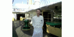 Ein Mann in weißer Kochuniform steht auf dem Deck eines Schiffes.