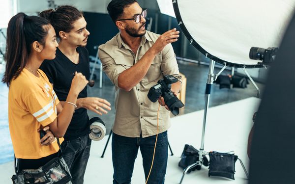 Fotograf hält Kamera in der Hand und zeigt Kunden das Fotostudio