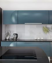 Cocina moderna con gabinetes azules, encimera negra, horno, microondas y decoración minimalista.