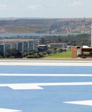Vista aérea de Brasília com prédios do Congresso Nacional ao fundo e heliporto em primeiro plano.