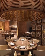 Restaurante con mesas elegantes, decoración de madera y luces cálidas, ambiente acogedor.