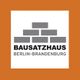 Logo von Bausatzhaus Berlin-Brandenburg: graue Ziegel, Text auf orangem Hintergrund.