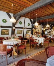 Gemütliches Café im Landhausstil mit rustikalen Holzbalken, weißen Tischdecken und Bildern an der Wand.