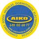 Círculo amarillo con el logo "AIKO", teléfono y dirección. Palabras: muebles, dormitorios, sofás.