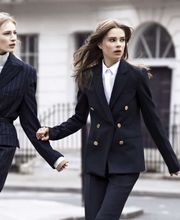 Due donne in abiti eleganti camminano per strada tenendosi per mano.