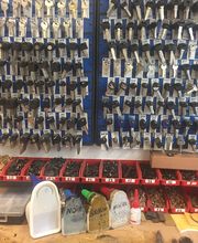 Wand mit vielen Schlüsselrohlingen und Regale mit Werkzeugen in einer Werkstatt.