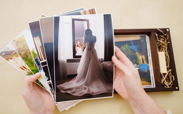 Person hält Hochzeitsbilder in der Hand