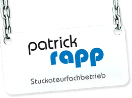 Schild mit der Aufschrift "Patrick Rapp Stuckateurfachbetrieb" hängt an einer Metallkette.