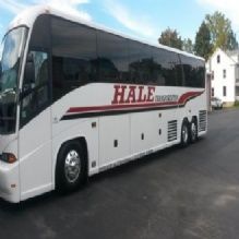 White tour bus labeled "Hale Transportation" parked on an asphalt surface.