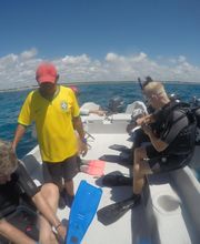 Personas en bote preparándose para bucear en el mar bajo un cielo azul.