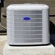 Outdoor air conditioning unit on a concrete pad against a building wall.