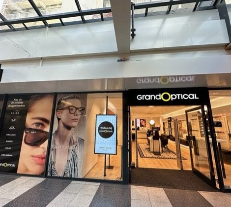 GrandOptical-winkel met brillenreclame op ramen en glazen automatische deuren.