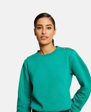 Mujer con jersey verde y cabello recogido, posa con fondo blanco.