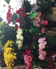 Verschiedene bunte Blumensträuße in Vasen, darunter Rosen, Lilien und gelbe Chrysanthemen.