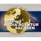Goldener Globus mit Text: "Agenthus Media-Agentur Sachsen" auf blauem Hintergrund.