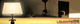 Lampe mit Schirm auf Tisch, Hintergrund mit Kamin und Schatten, Text "LEUCHTE".