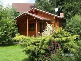 Holzhaus im Garten, umgeben von üppigem Grün und Blumen, sonniger Tag, Aufnahmedatum 31.07.2005.
