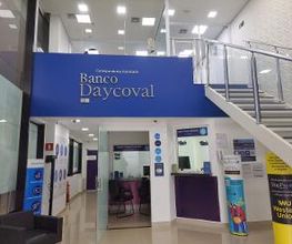 Interior do Banco Daycoval com cartazes na parede e uma escada ao lado.