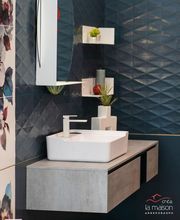 Bagno moderno con lavabo bianco, pareti blu e motivo floreale.