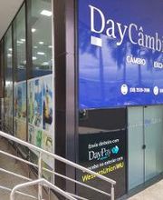 Fachada de uma casa de câmbio com o nome "DayCâmbio" e um cartaz azul.